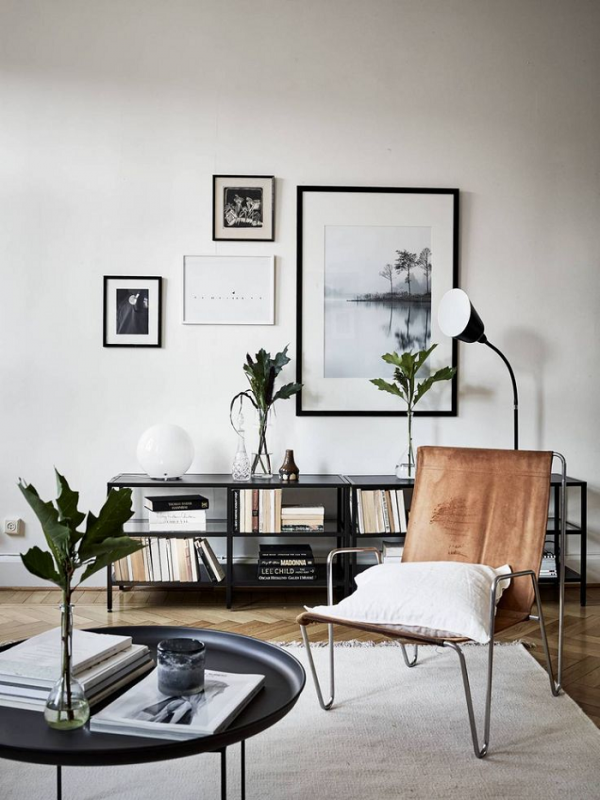 a Scandinavian living room with a tan leather sling chair with live plants