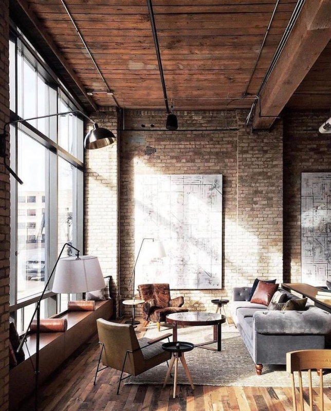 masculine industrial living room with exposed brick wall and leather accent chairs. 