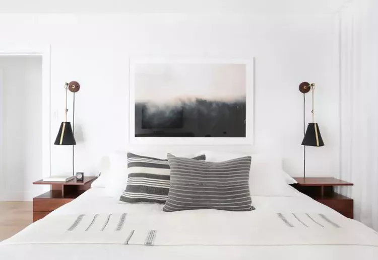 minimalist all white bedroom with a large bold wall art above the bed for drama and a touch of color.