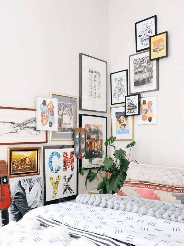 a bright white bedroom with a gallery wall mixing all types of wall art including bold art pieces