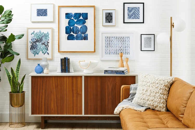 white brick wall with a modern bold wall art gallery wall and a rich warm wood credenza with accessories for a stylish space