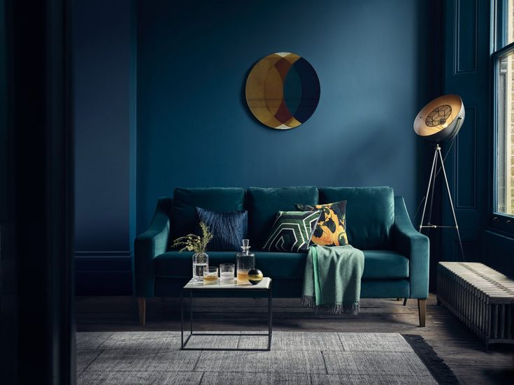 modern moody living room with dark navy blue wall colo and hunger green velvet sofa