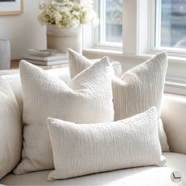 an image showing how to arrange throw pillows on a couch with three pillows in different sizes, in a light and airy living room